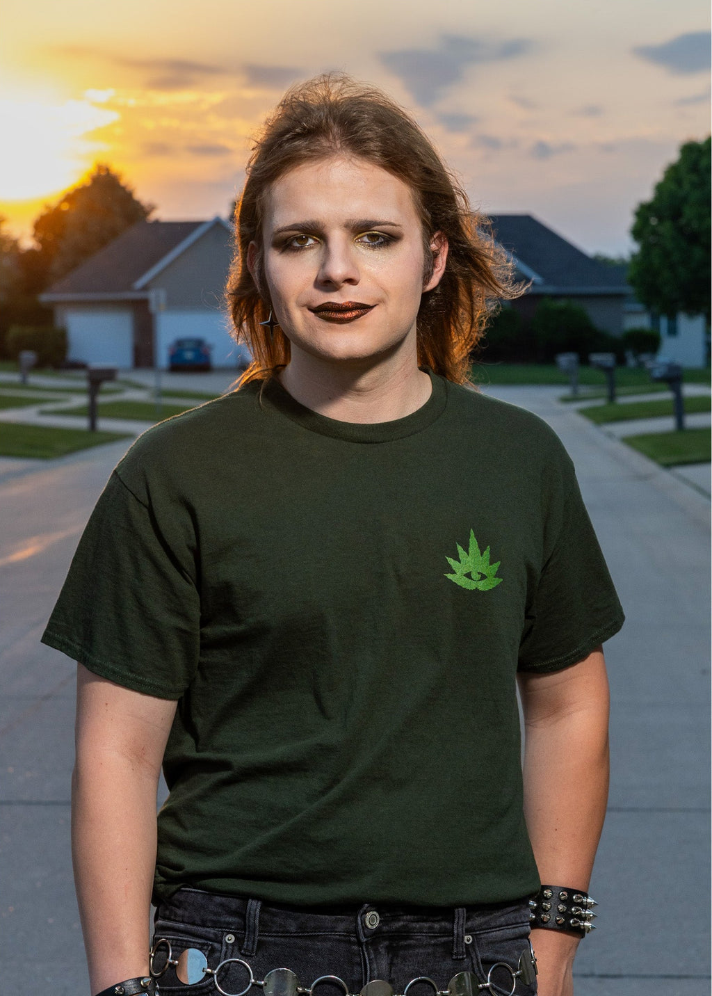 Person wearing a green t-shirt with a leaf design outdoors during sunset.